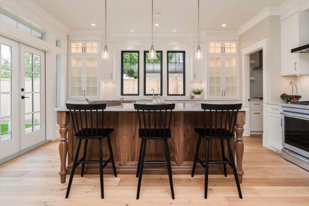 bespoke kitchen design, walnut wood kitchen island, spacious kitchen island, polished quartz countertops, statement pendants light the island, farmhouse style counter stools, black counter stools, black interior windows, Maxine Whitehead Design