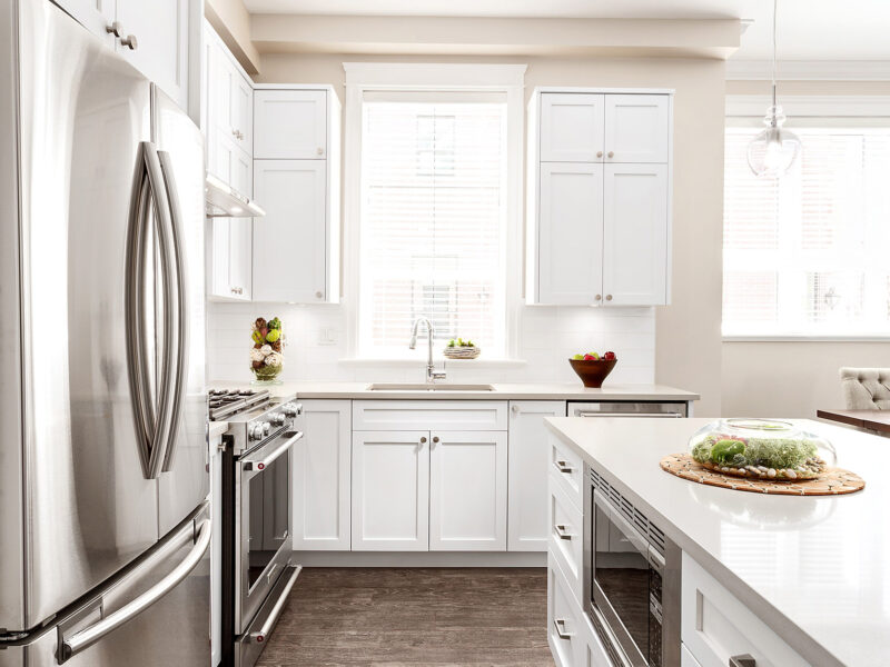 bespoke kitchen design, white shaker kitchen cabinets, spacious kitchen island, polished quartz countertops, statement pendants light the island, open plan kitchen, Maxine Whitehead Design