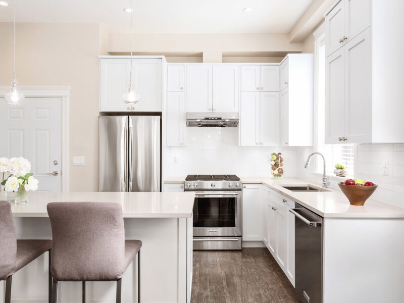 bespoke kitchen design, white shaker kitchen cabinets, spacious kitchen island, polished quartz countertops, statement pendants light the island, open plan kitchen, Maxine Whitehead Design