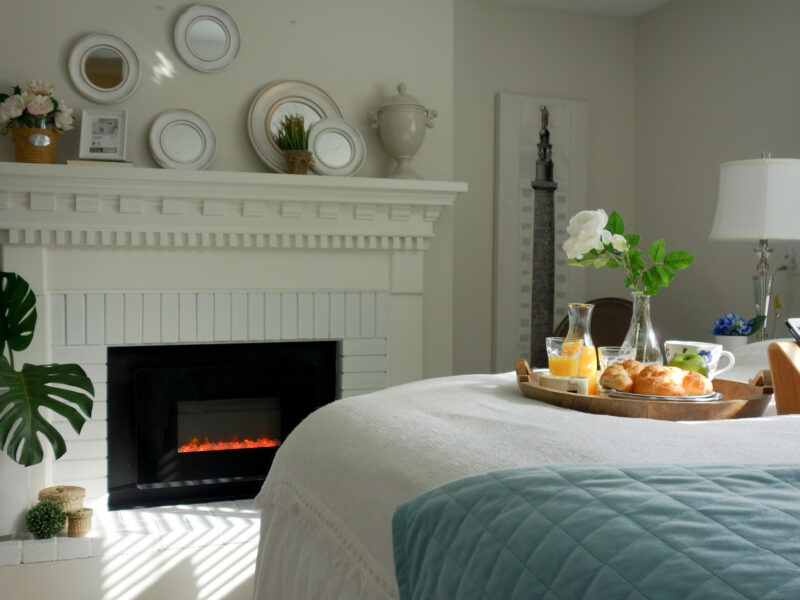 breezy vacation house bedroom, casual lived-in feel, soft cotton white bed linens, fireplace adds a dramatic focal point, Maxine Whitehead design