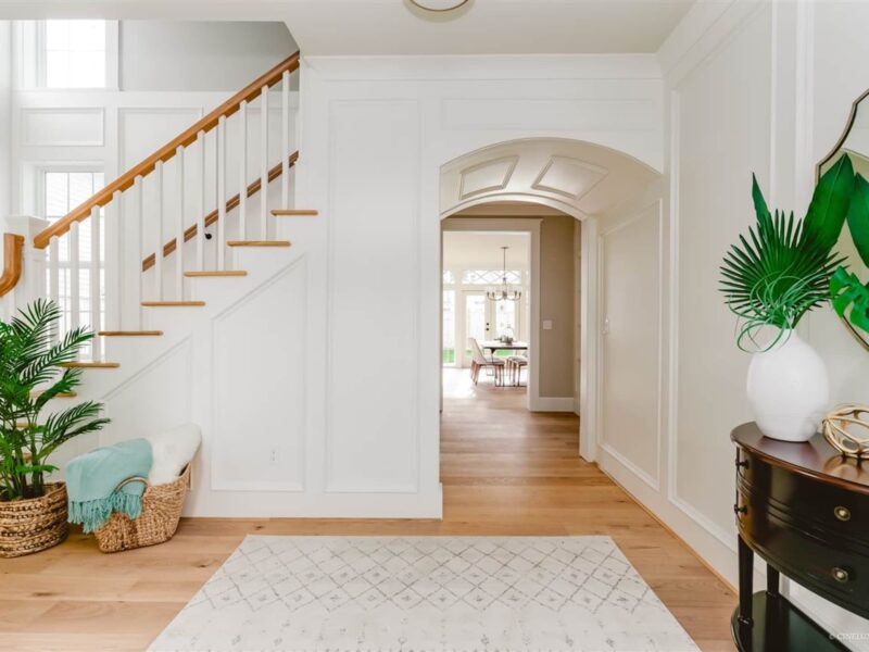 Classic interior design meets modern living, welcoming entry leads to an doorway arch, soft patterned rug underfoot, warm and inviting wide plank wood flooring, historic charm and unique character, a graceful staircase greets guests, Maxine Whitehead design