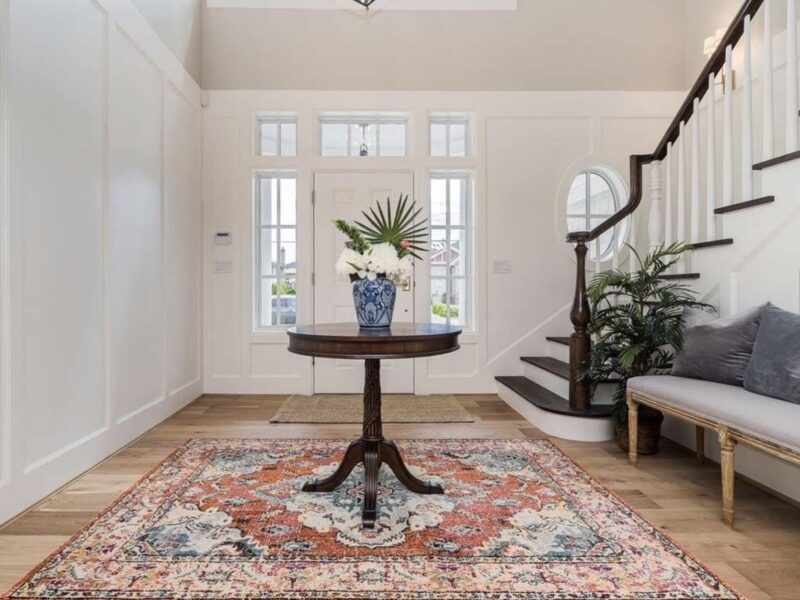 grand staircase, grand entrance, bright airy welcoming entryway, statement rug, timeless style, oval window focal point, Maxine Whitehead design