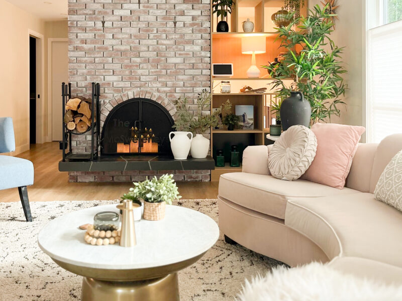 Mid-century modern living room, luxe curved velvet sofa, hourglass coffee table, open plan living, soft patterned rug underfoot, brick fireplace, Maxine Whitehead design