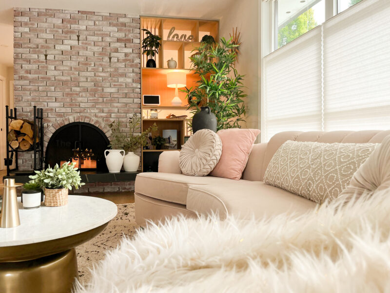 Mid-century modern living room, luxe curved velvet sofa, hourglass coffee table, open plan living, soft patterned rug underfoot, brick fireplace, Maxine Whitehead design